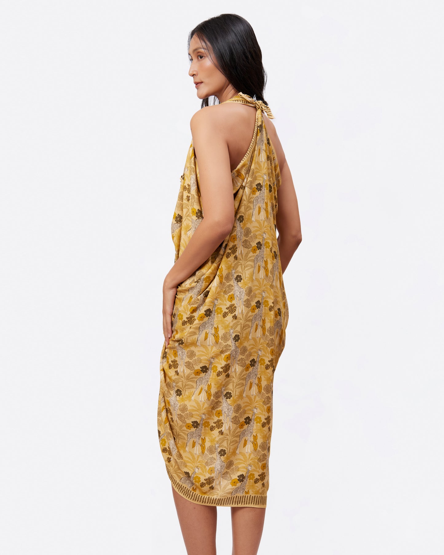 Woman wearing a yellow pareo with safari and giraffe pattern as a dress