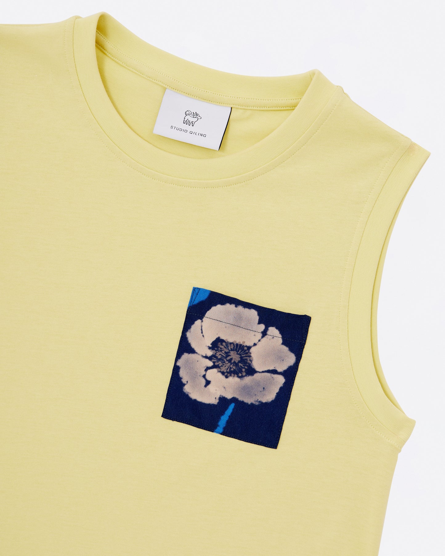 Close up of a yellow sleeveless cotton jersey tank dress with a poppy flower pocket detail