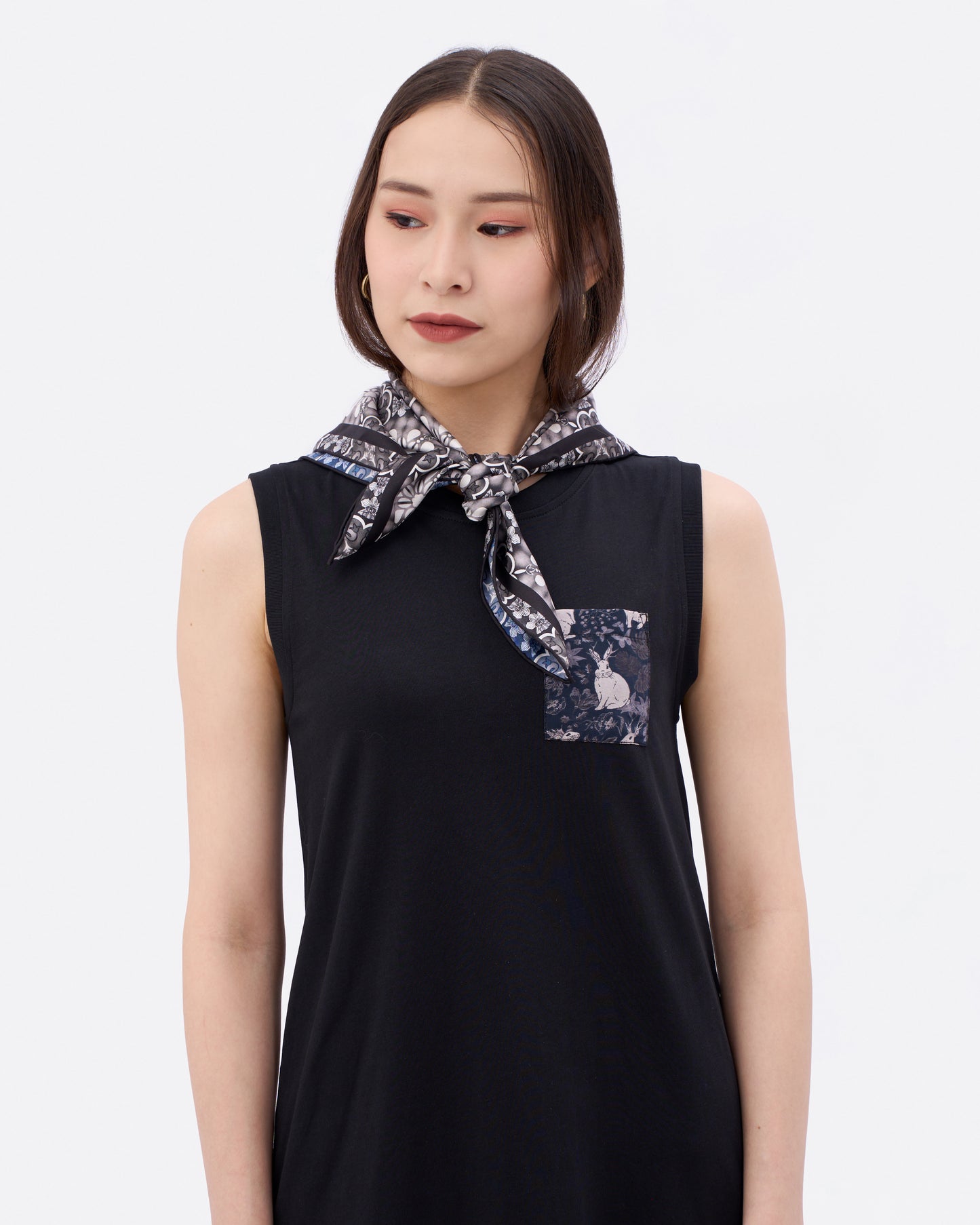 Woman wearing a black sleeveless cotton dress with a reversible silk scarf with peranakan orchid print around her neck