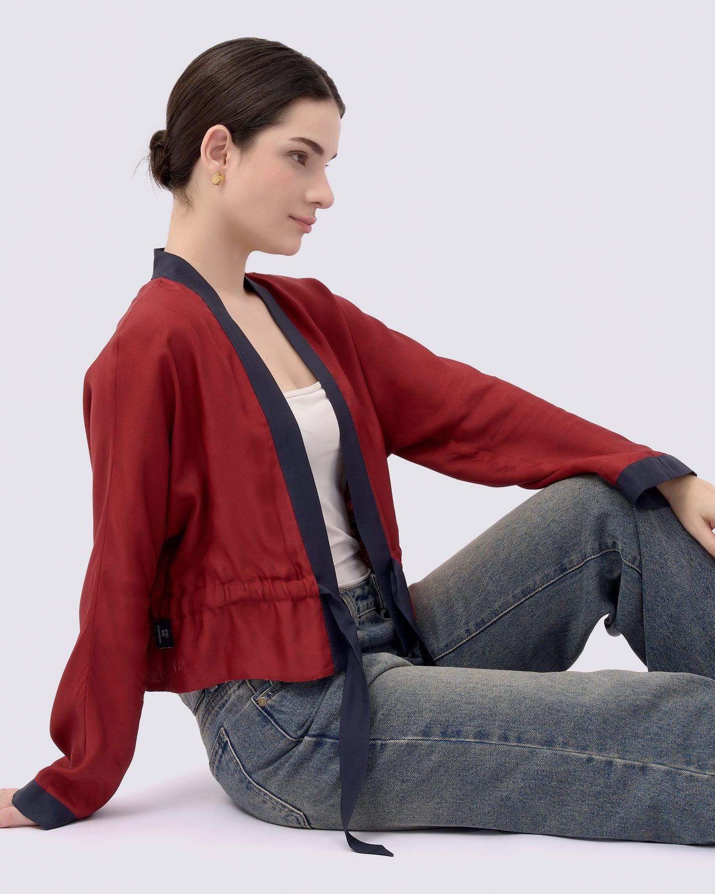 Woman wearing a red silk blend reversible kimono style outerwear and blue jeans