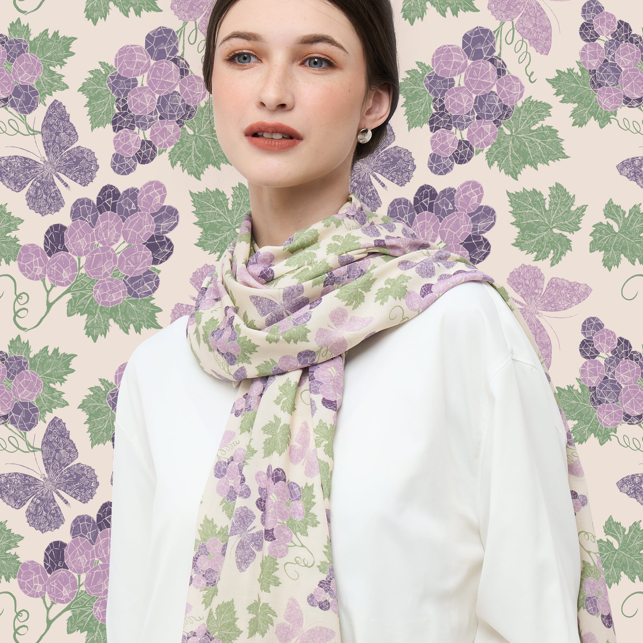 Woman wearing a floral shawl scarf with a hand-drawn amethyst grapes patterned background