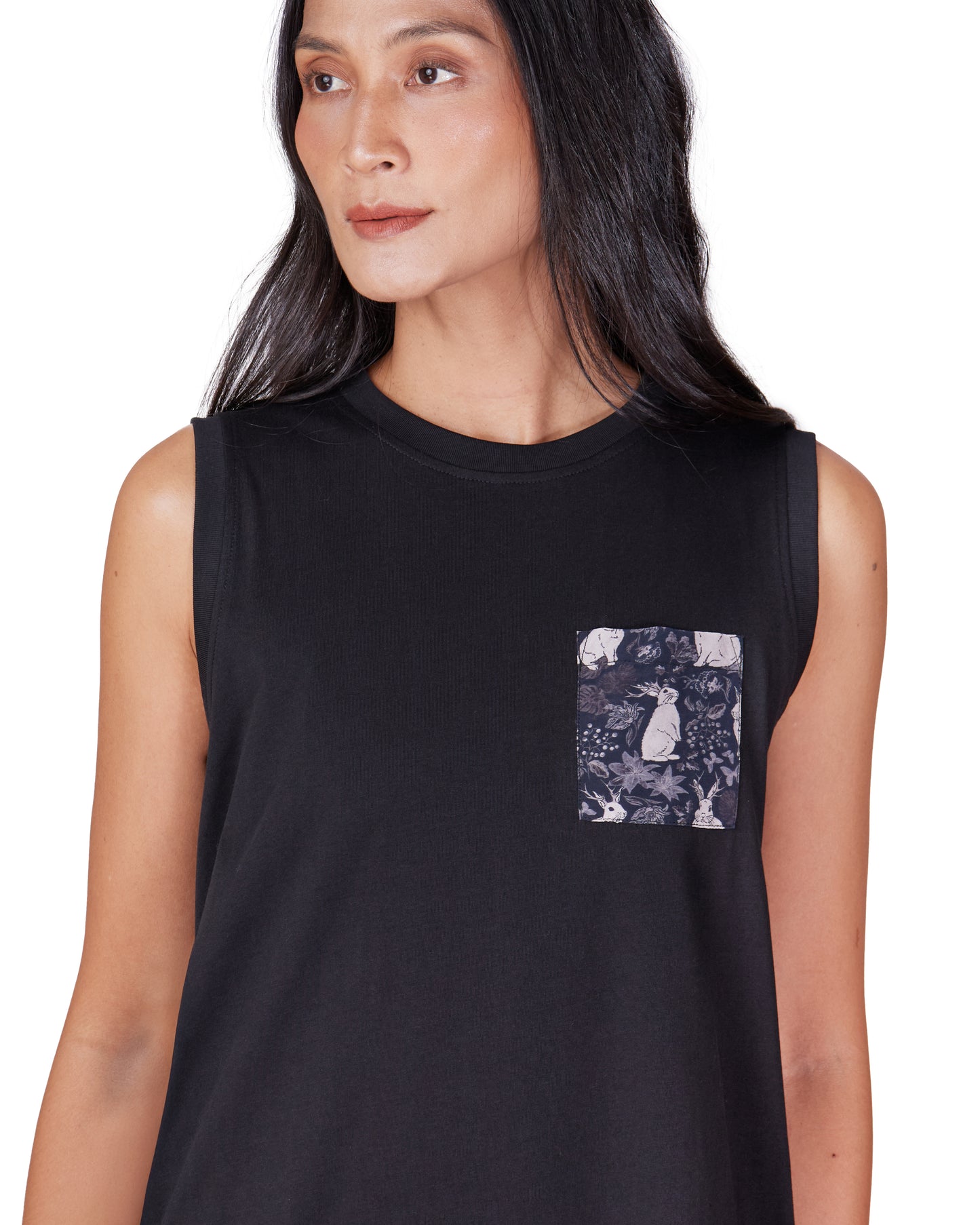 Woman wearing a black sleeveless cotton tank dress with a printed pocket design on a white background
