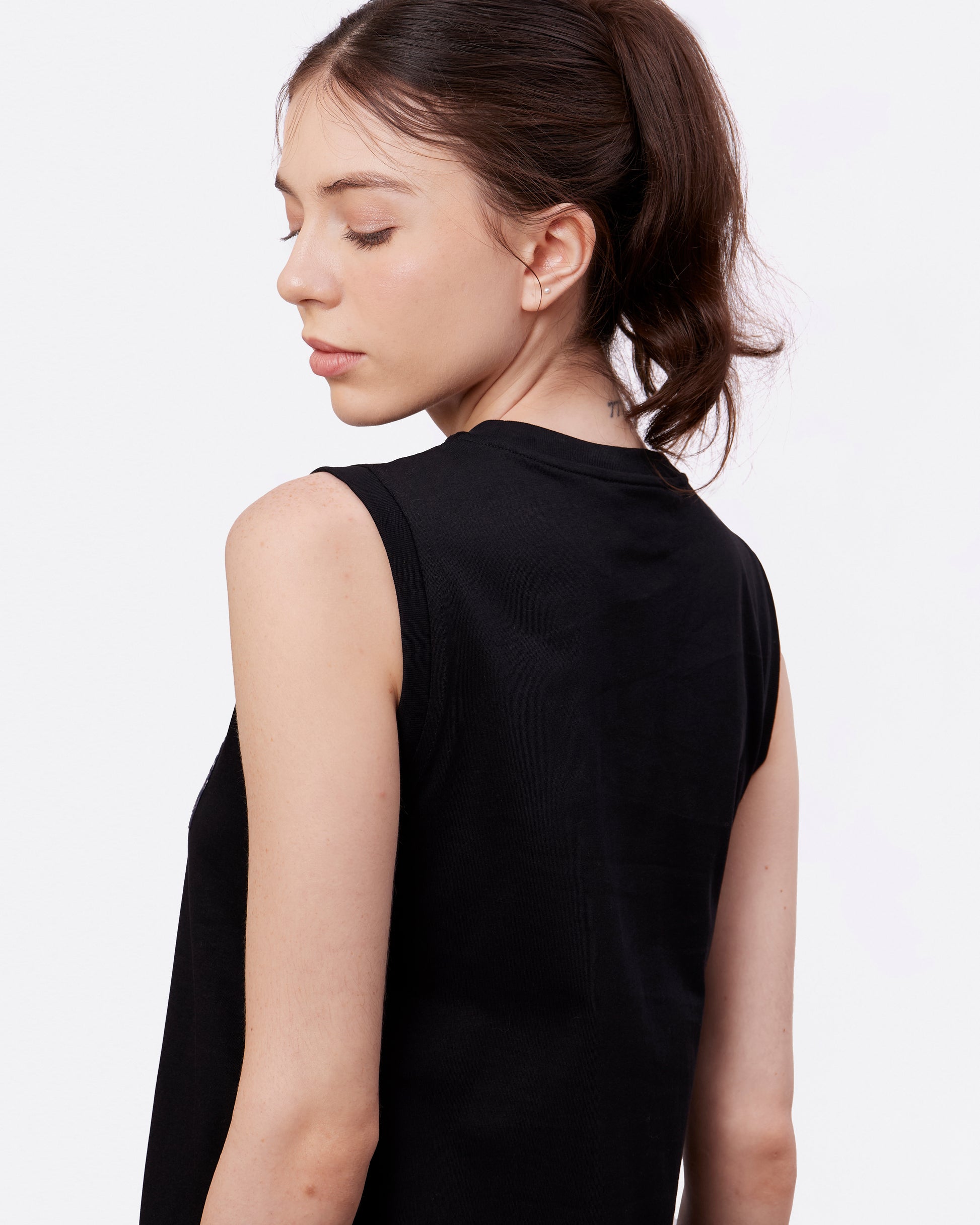 Back view of woman wearing a black sleeveless cotton tank dress against a white background