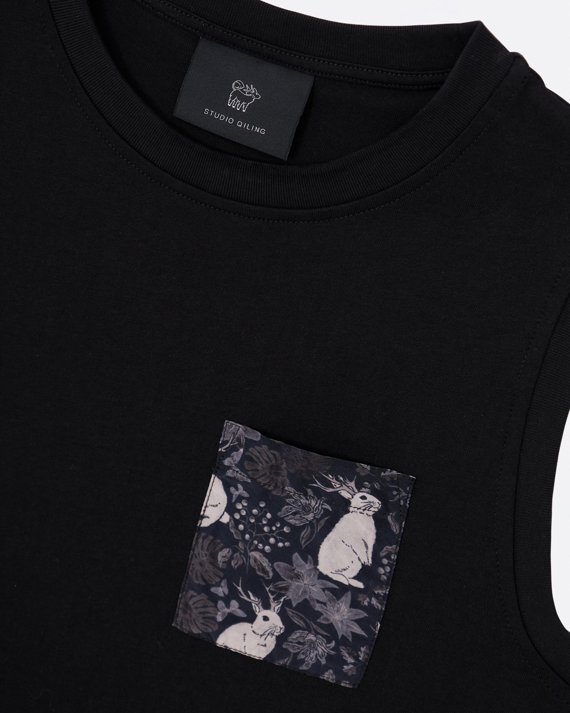 Black cotton tank dress with a pocket featuring a hand drawn floral and rabbit pattern