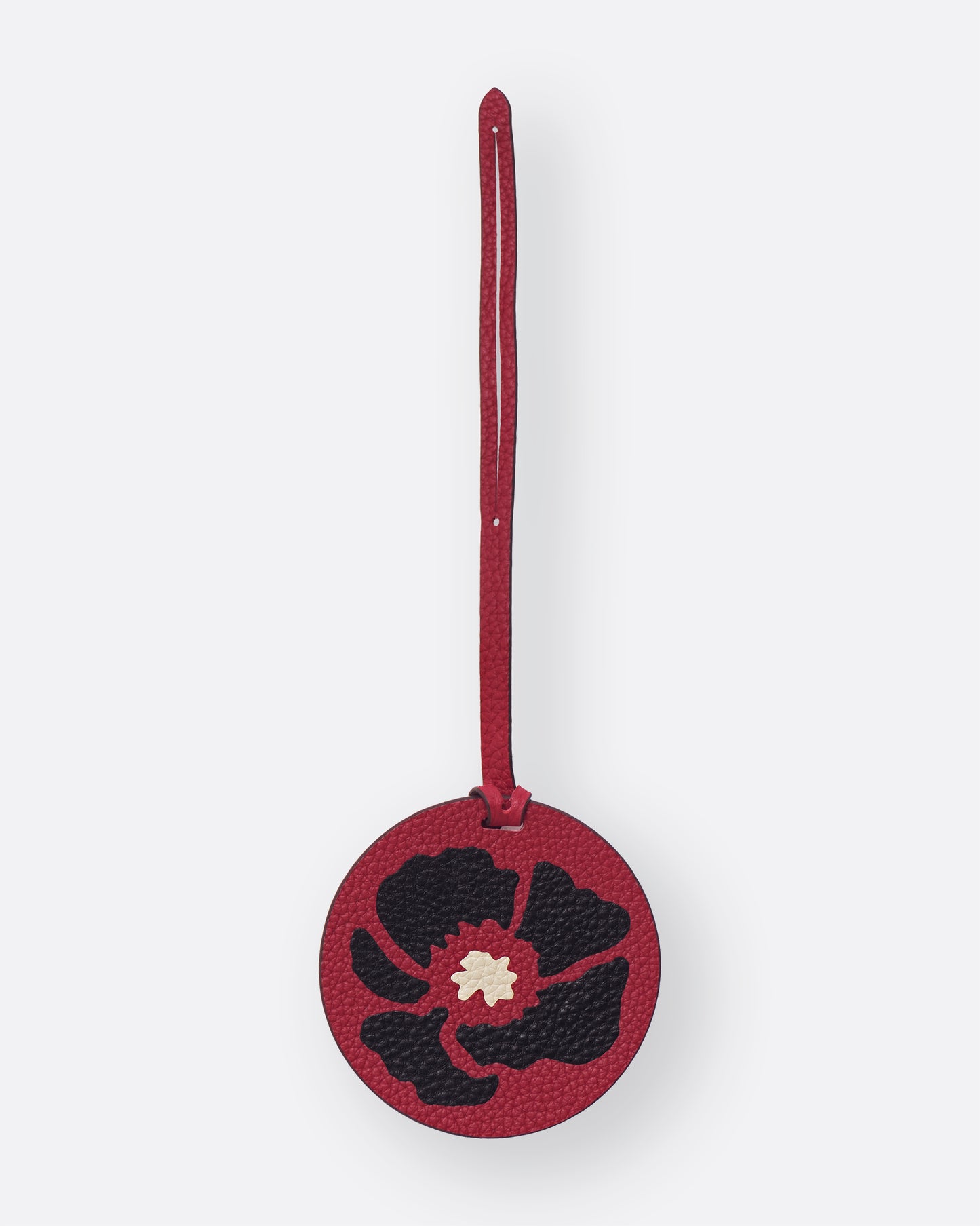 Round red leather bag charm with black Dancing Poppies marquetry flower, front view