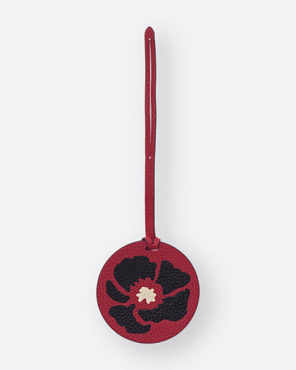 Round red leather bag charm with black Dancing Poppies marquetry flower, front view