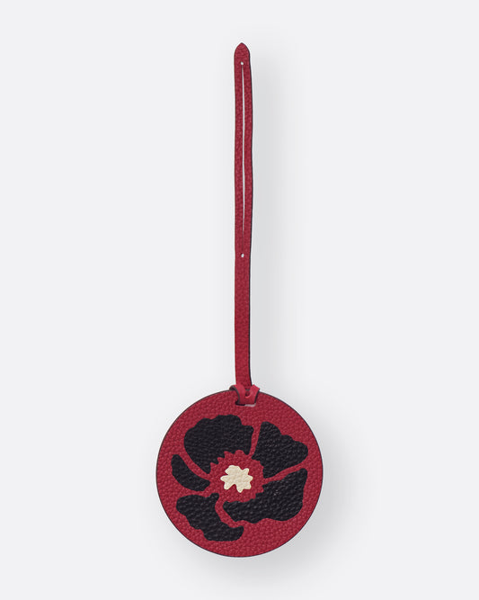 Round red leather bag charm with black Dancing Poppies marquetry flower, front view