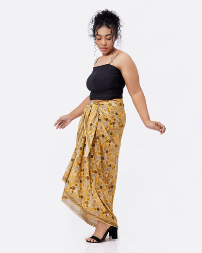 Woman wearing a black top and yellow giraffe patterned shawl as a skirt