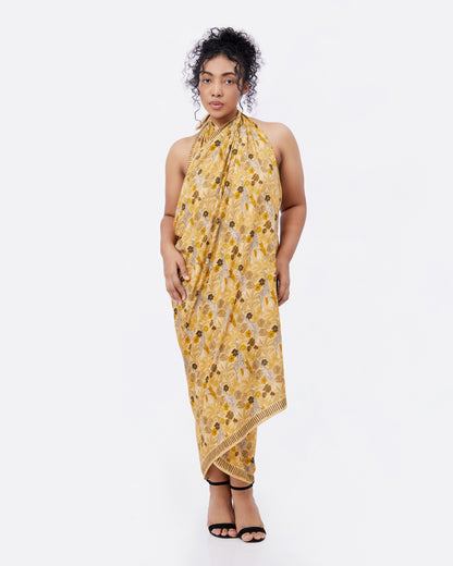Woman wearing a yellow pareo with hand illustrated giraffe print as a halter dress 