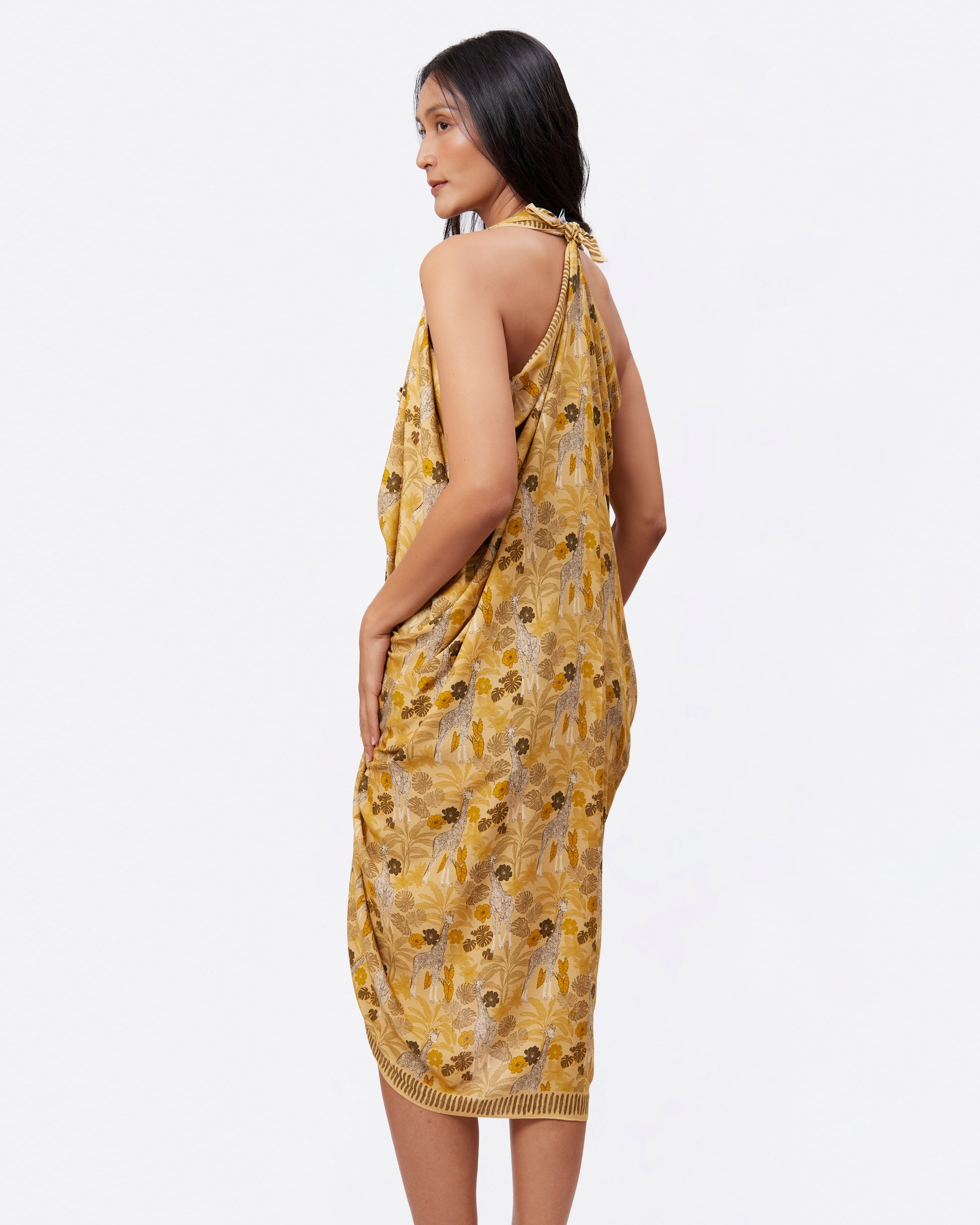 Woman wearing a yellow pareo with safari and giraffe pattern as a dress 