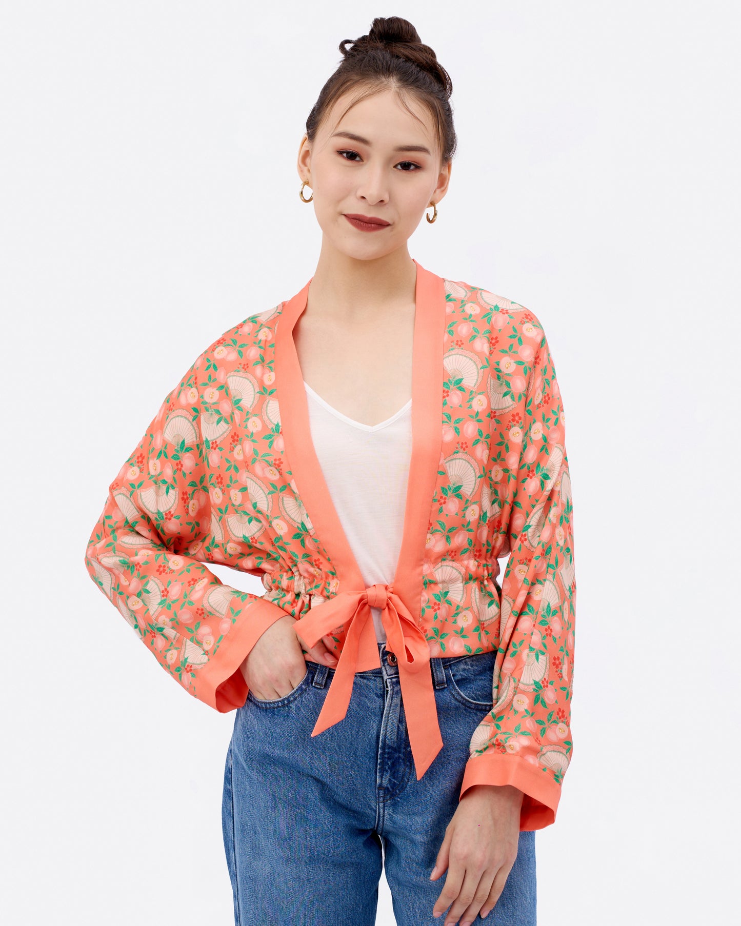 Woman wearing a reversible silk blend kimono-style jacket with prints over a white top and blue jeans