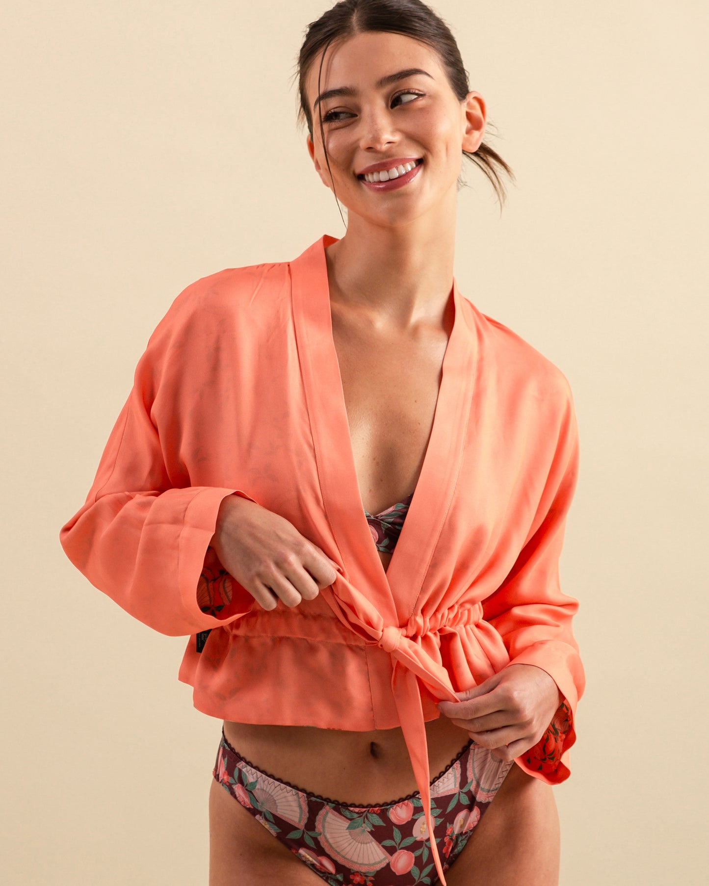 Studio Qiling x Perk by Kate. Woman wearing a coral kimono style cover up over a patterned lingerie