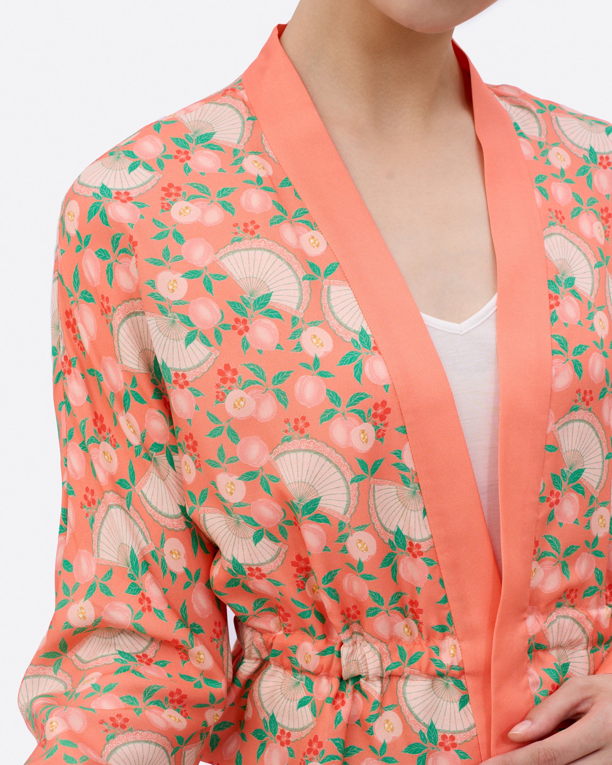 Lady wearing a patterned kimono with hand illustrated peaches, ingots, fans and florals in the design