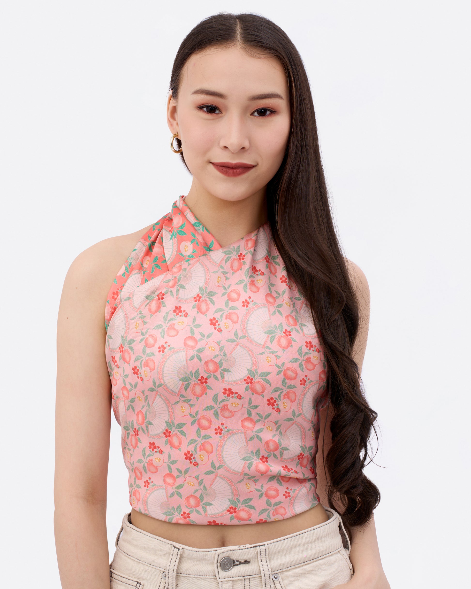 Woman wearing a patterned reversible silk scarf in pink and coral colour as a halter top