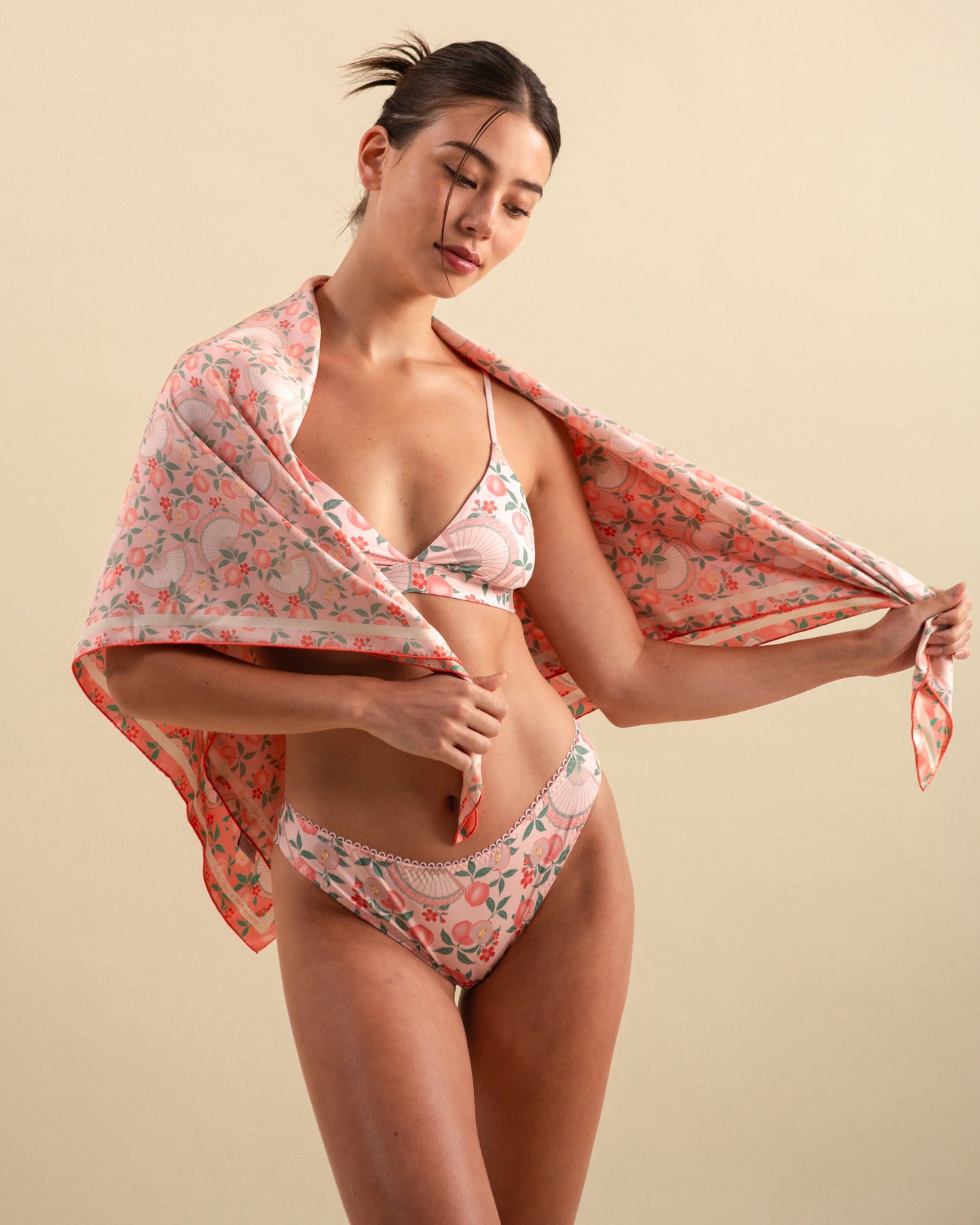 Studio Qiling x Perk by Kate. Woman wearing a patterned bra set with a matching reversible silk scarf in pink and coral colour.