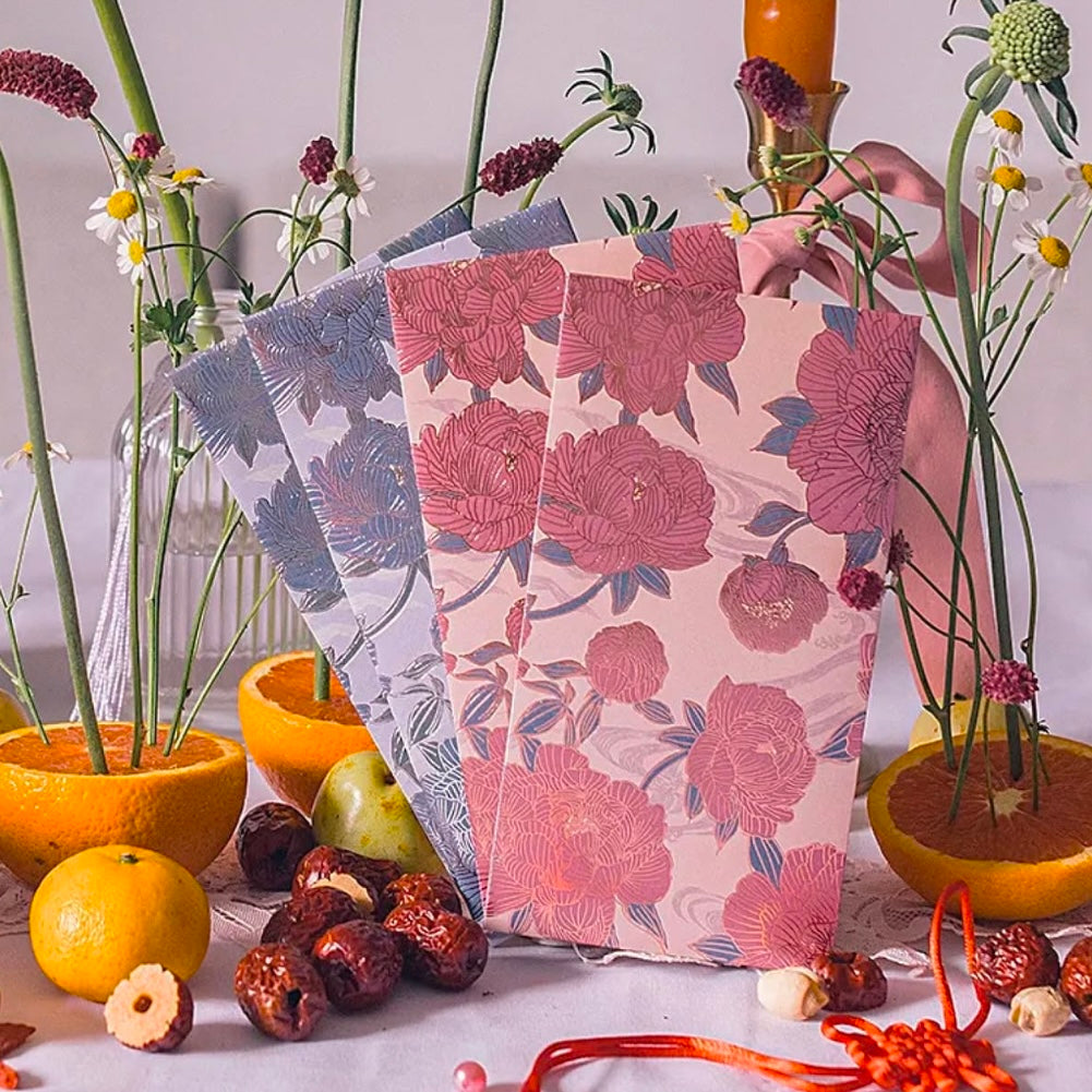 Floral-patterned chinese new year red packets with decorative elements on a table.