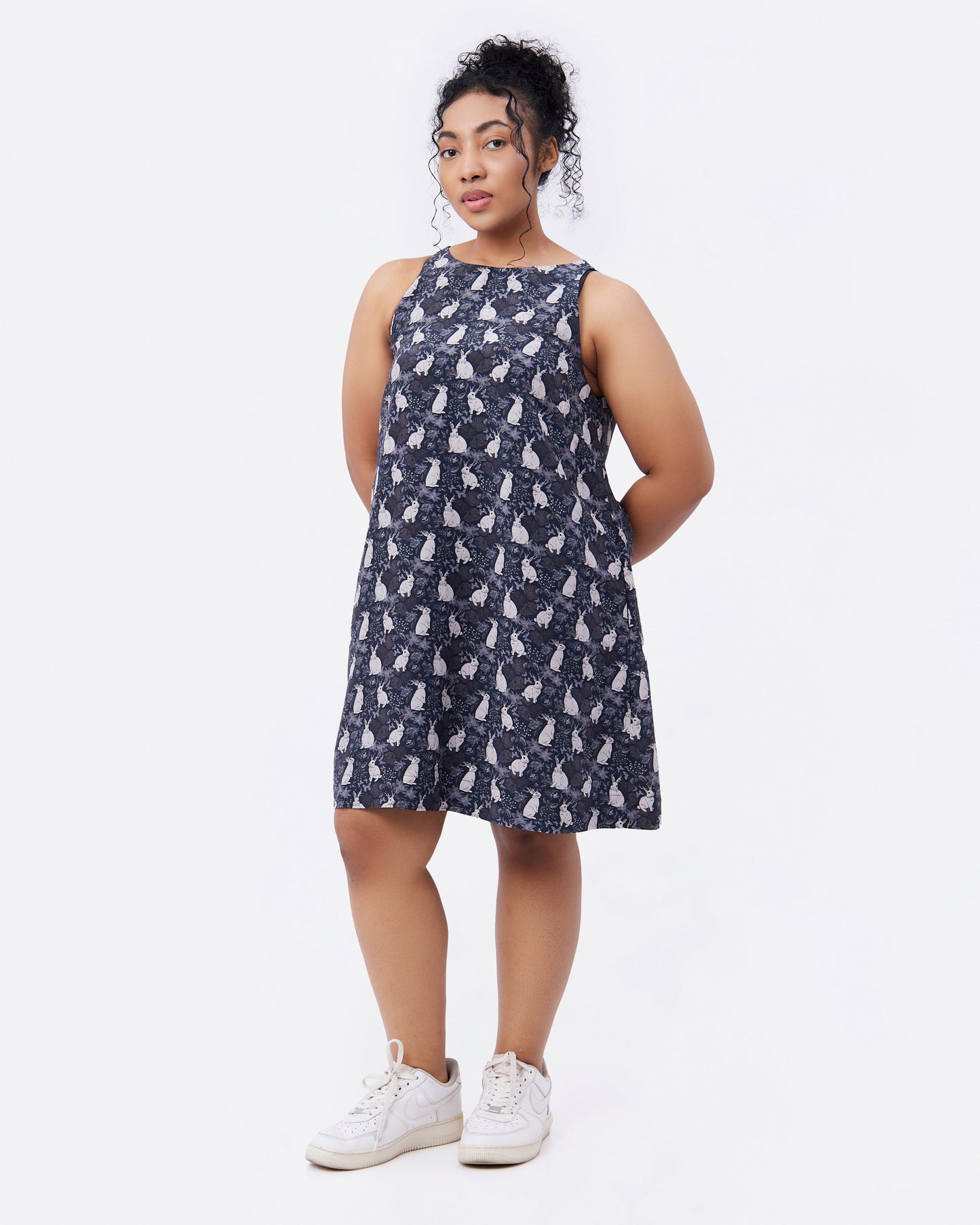 Woman wearing a black silk blend dress with hand drawn mythical rabbit pattern on a white background