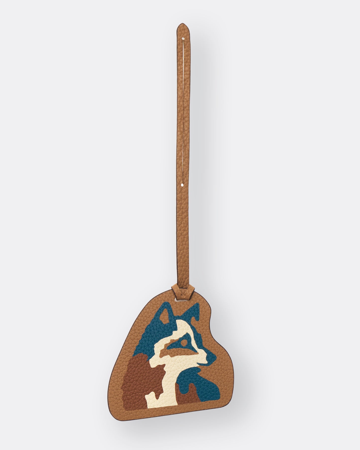 Light brown leather bag charm with teal Kitsune fox marquetry artwork, front view