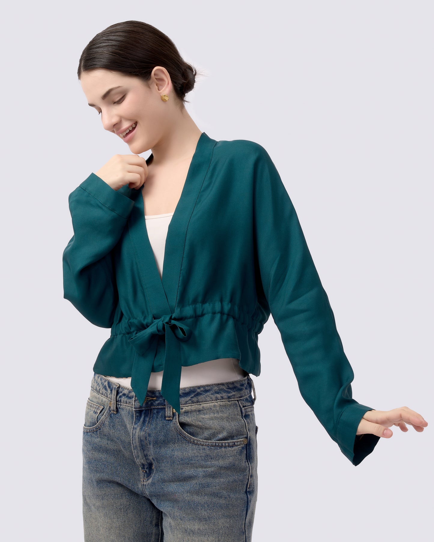 Woman wearing a teal green reversible silk blend reversible kimono style cardigan and blue jeans 