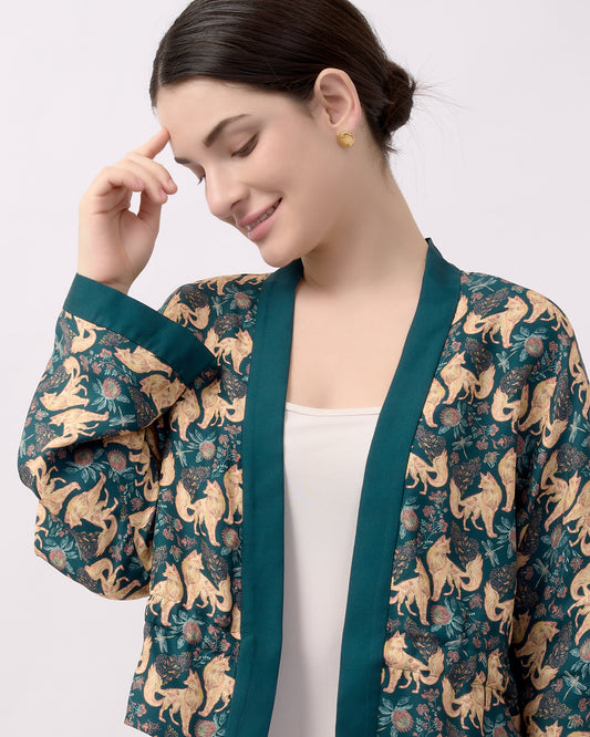 Woman wearing a teal green reversible kimono style jacket with hand illustrated kitsune design on one side and solid teal colour on the other side