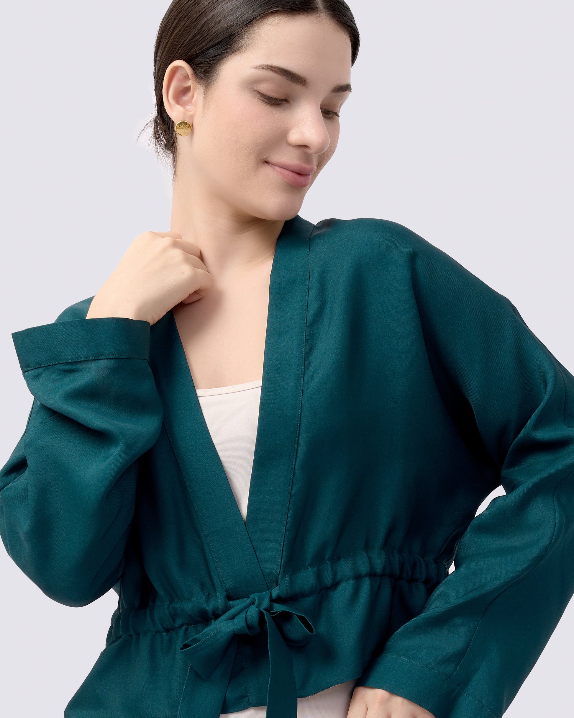 Woman wearing a teal green reversible silk blend kimono style jacket blouse with a white tank top