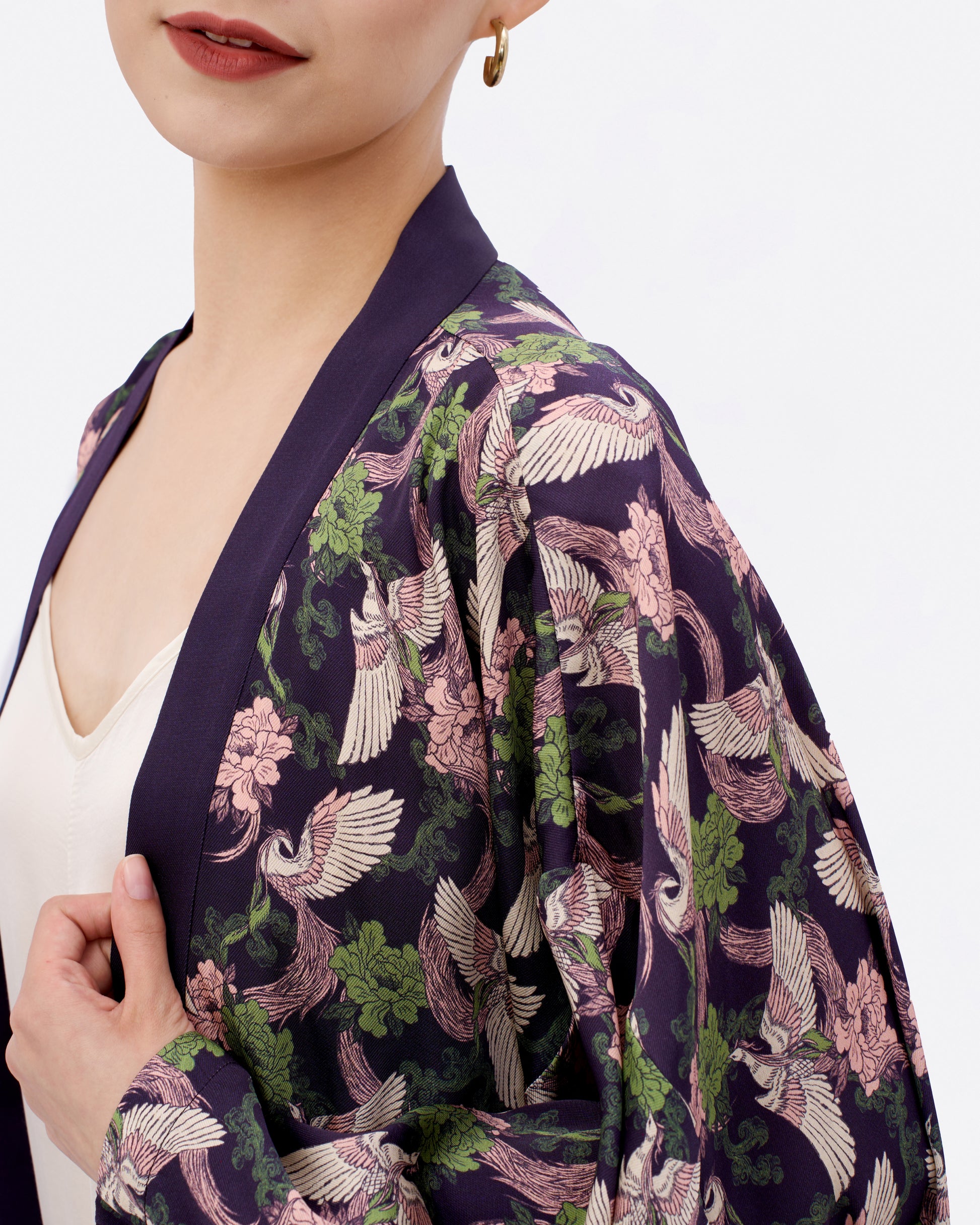 Woman wearing a dark purple kimono style cardigan with phoenix and floral pattern over a white dress