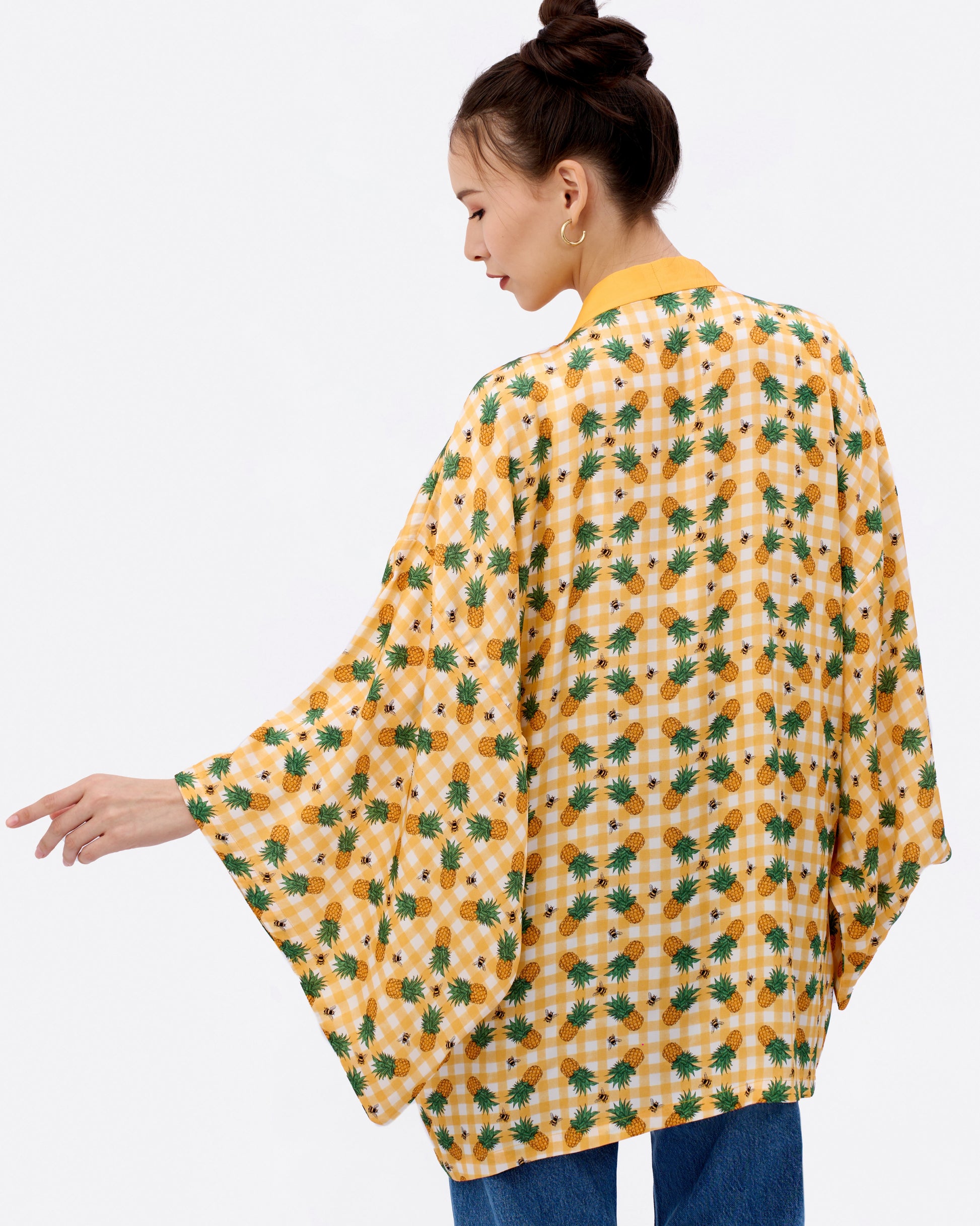 Woman wearing a yellow flowy japanese cut kimono with checkered pineapple pattern 