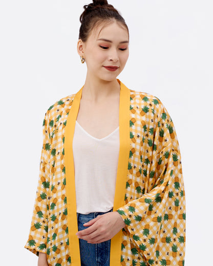 Woman wearing a yellow japanese style silk blend kimono with pineapple, bees and checkered pattern 