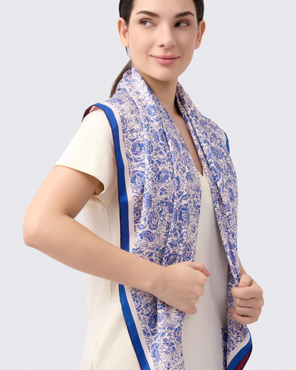 Woman wearing a blue and white patterned reversible silk scarf with porcelain style hand drawn print with a white cotton jersey dress