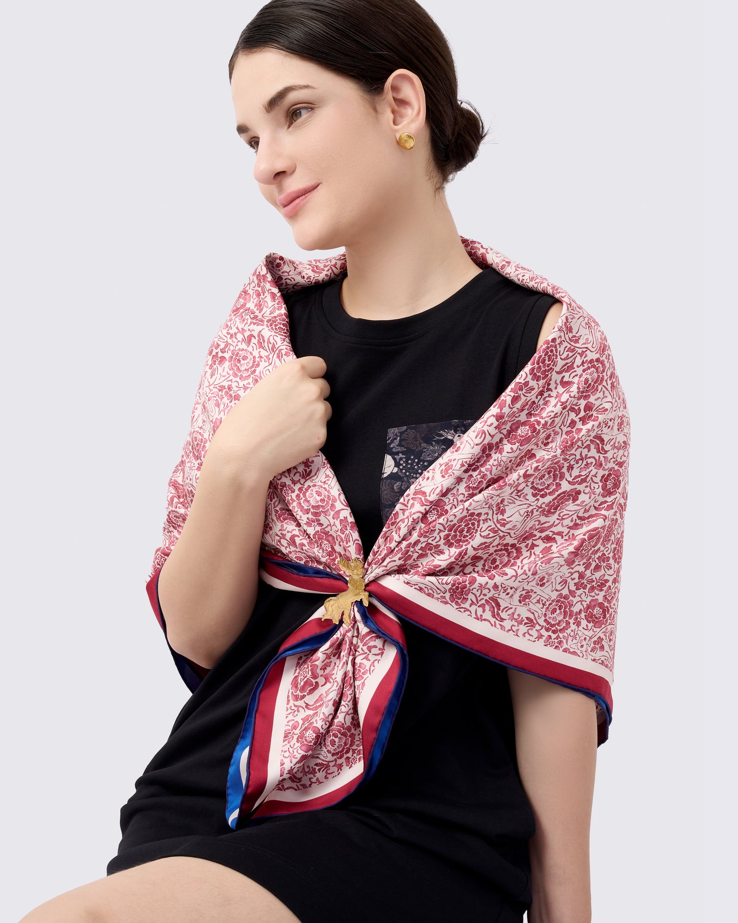 Woman wearing a red and white patterned reversible silk scarf with hand drawn porcelain style print with a gold scarf ring