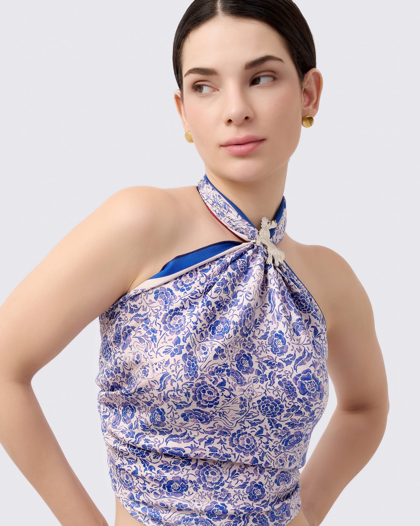 Woman wearing a blue and white porcelain style pattern reversible silk scarf as a halter top with a silver scarf ring
