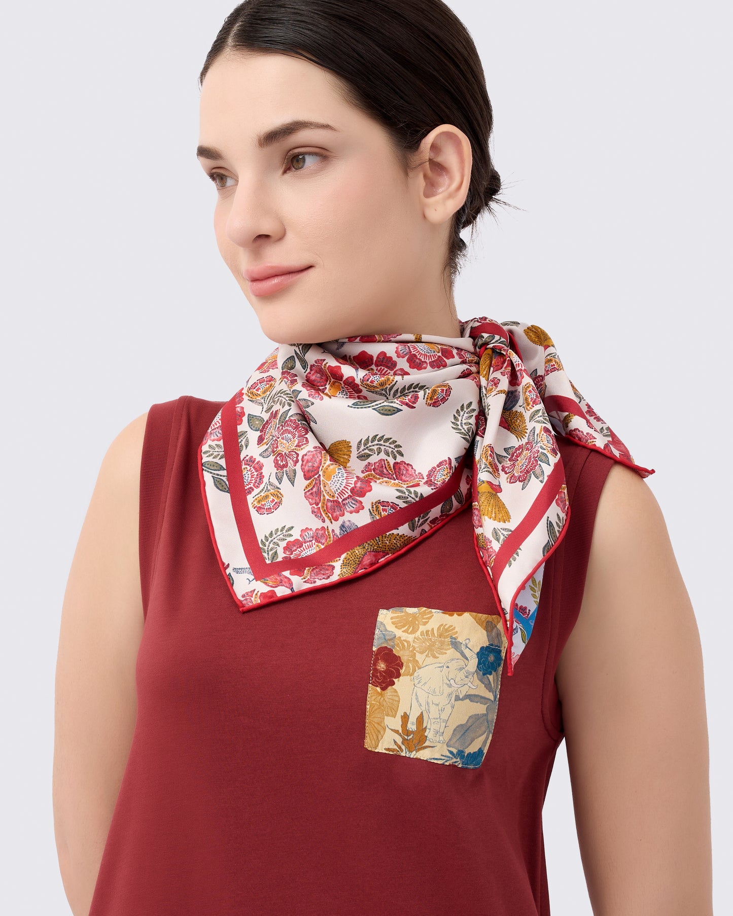 Woman wearing a reversible silk scarf with hand-drawn batik design with florals and crimson sunbird design