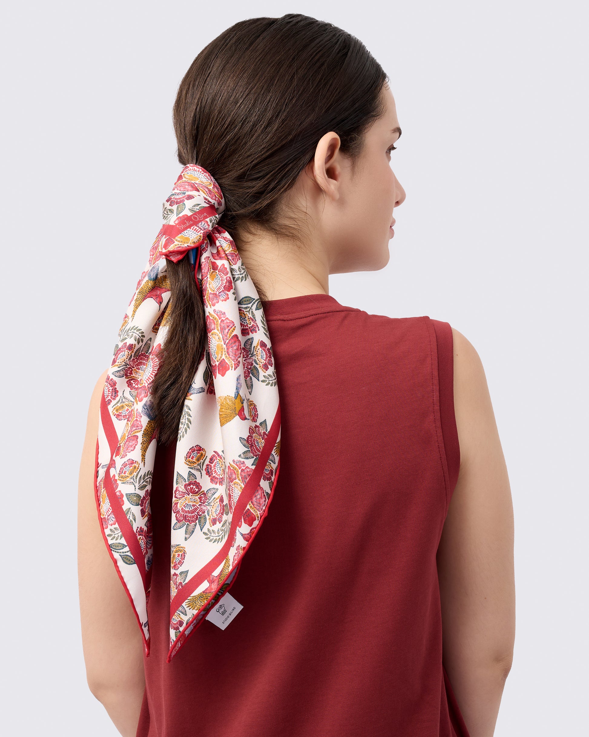 Woman wearing a reversible silk scarf with hand-drawn batik design with florals and crimson sunbird design