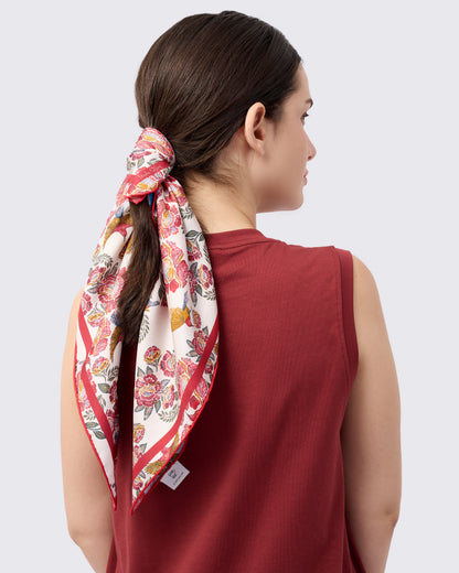 Woman wearing a reversible silk scarf with hand-drawn batik design with florals and crimson sunbird design