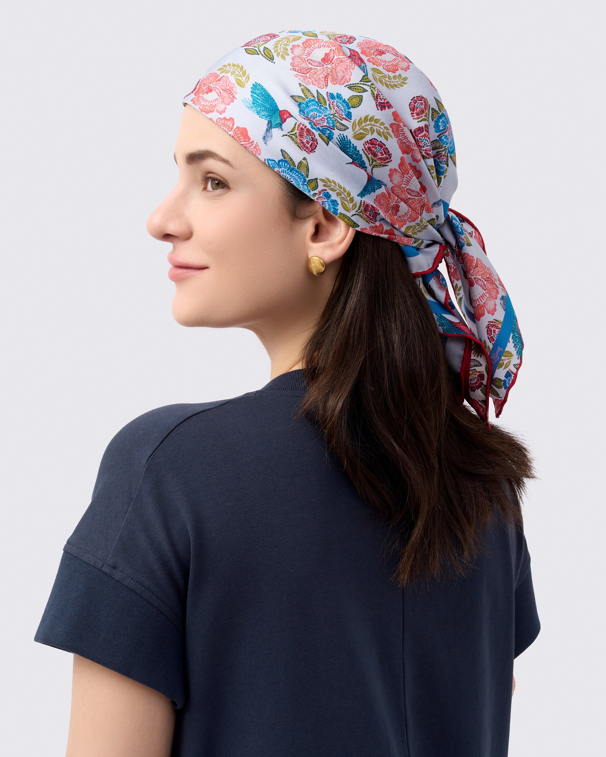 Woman wearing a reversible silk scarf with hand-drawn batik design with florals and crimson sunbird design
