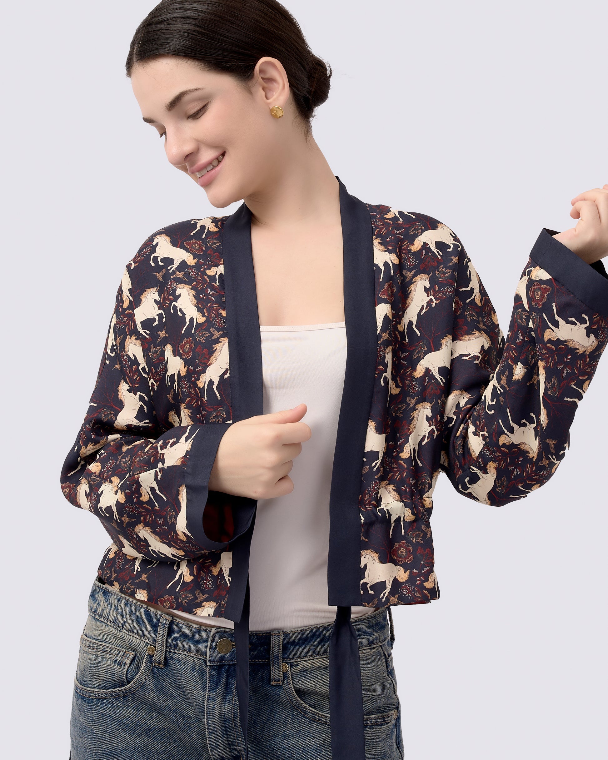 Woman wearing a patterned cropped kimono style jacket with hand-drawn unicorn print on one side and a maroon solid colour on the other side