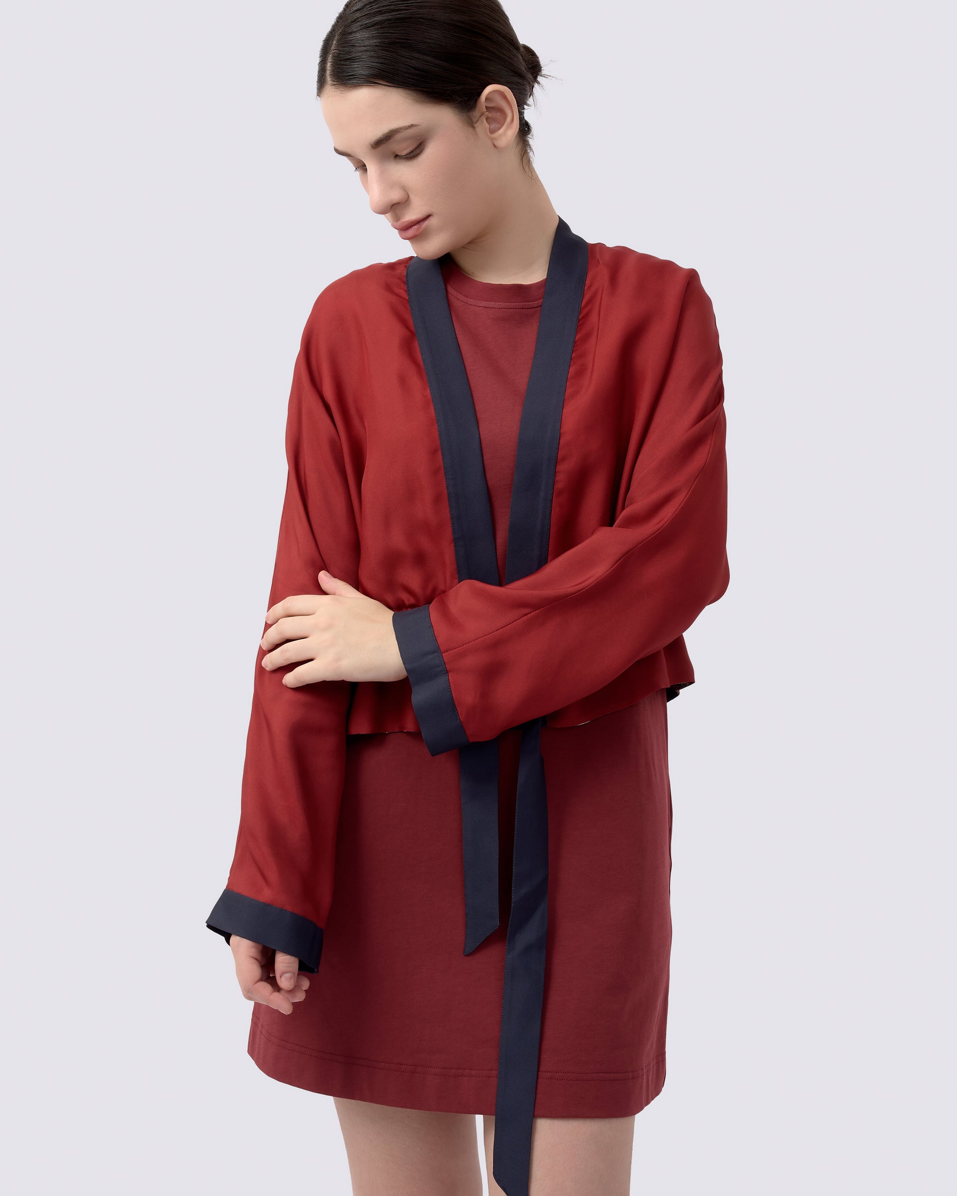 Woman wearing a maroon red reversible kimono style silk blend cardigan with navy trim 