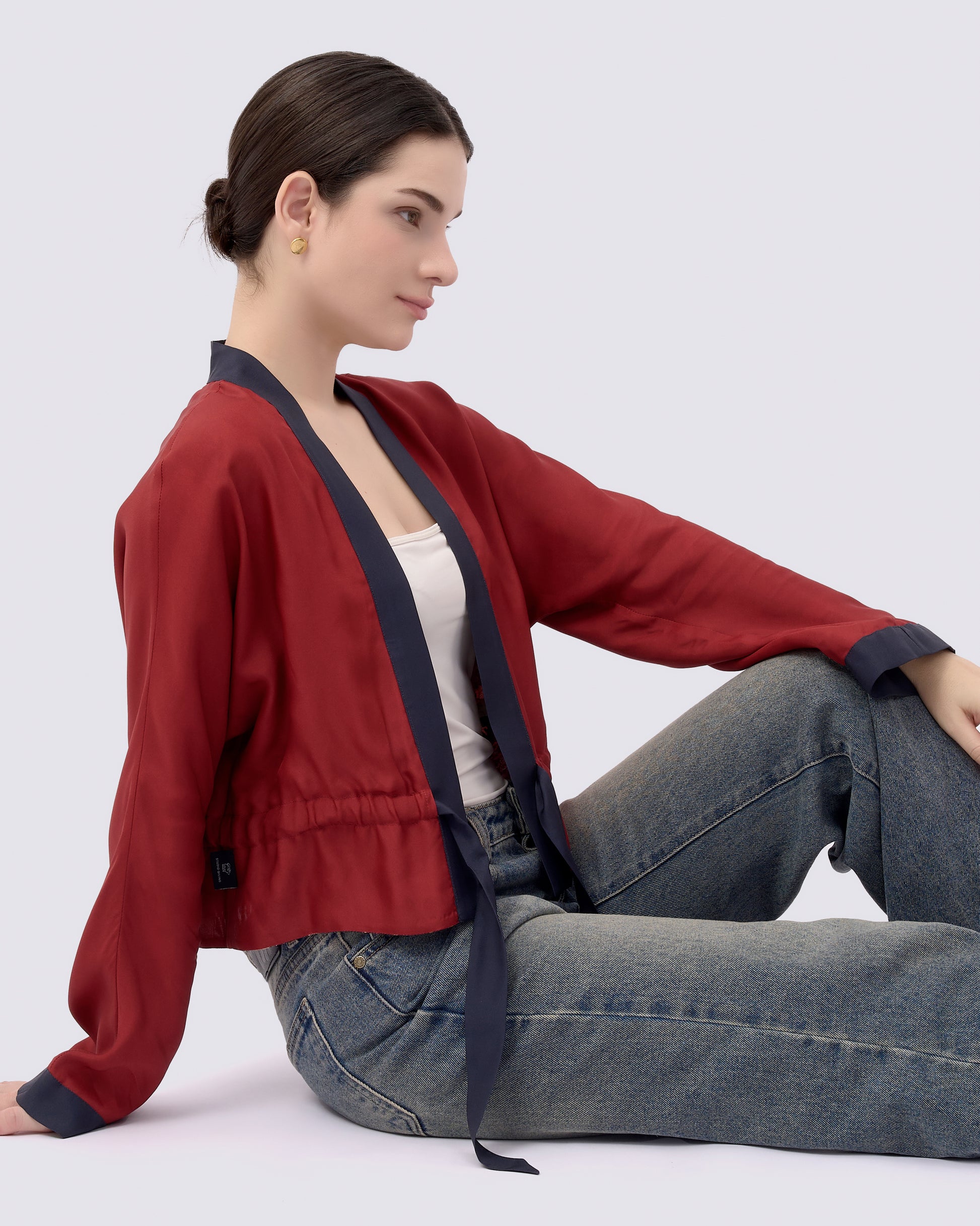 Woman wearing a red silk blend reversible kimono style outerwear and blue jeans 